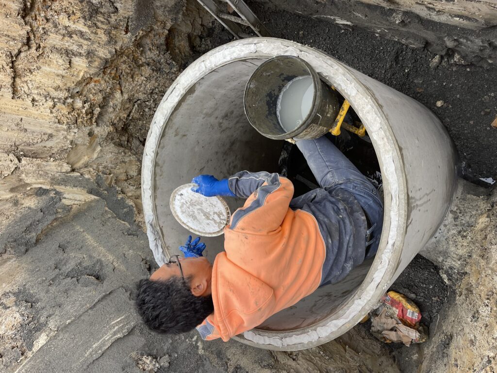 Worker inside a large concrete stormwater pipe