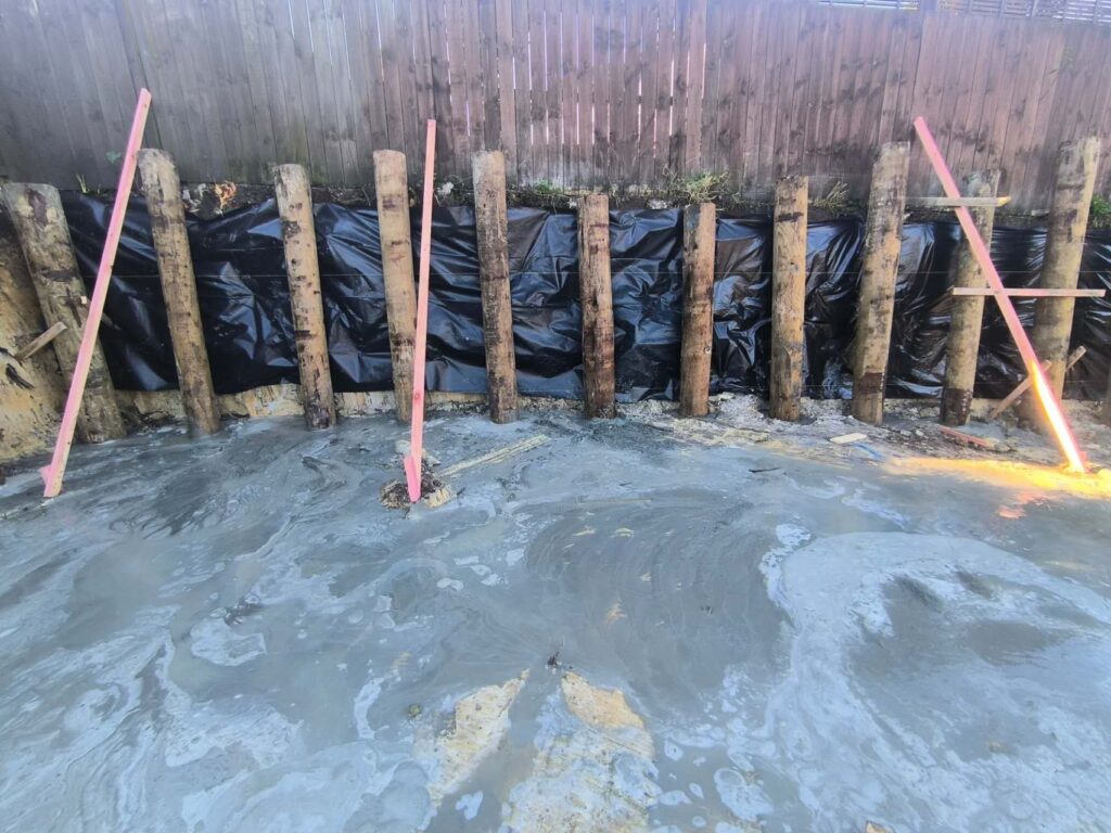 Timber pole retaining wall with drainage lining